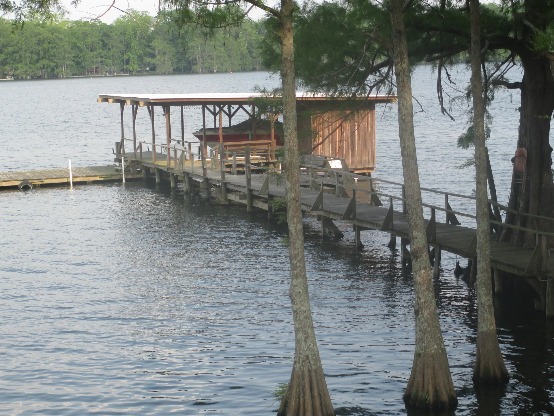 Private wooden boat dock with covered slip extending over a lake